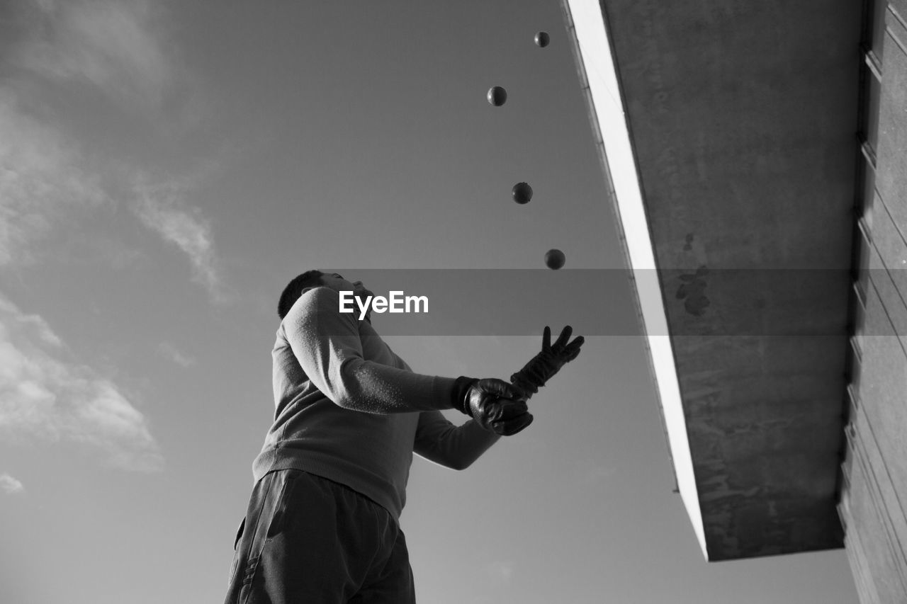 Low angle view of man playing with balls