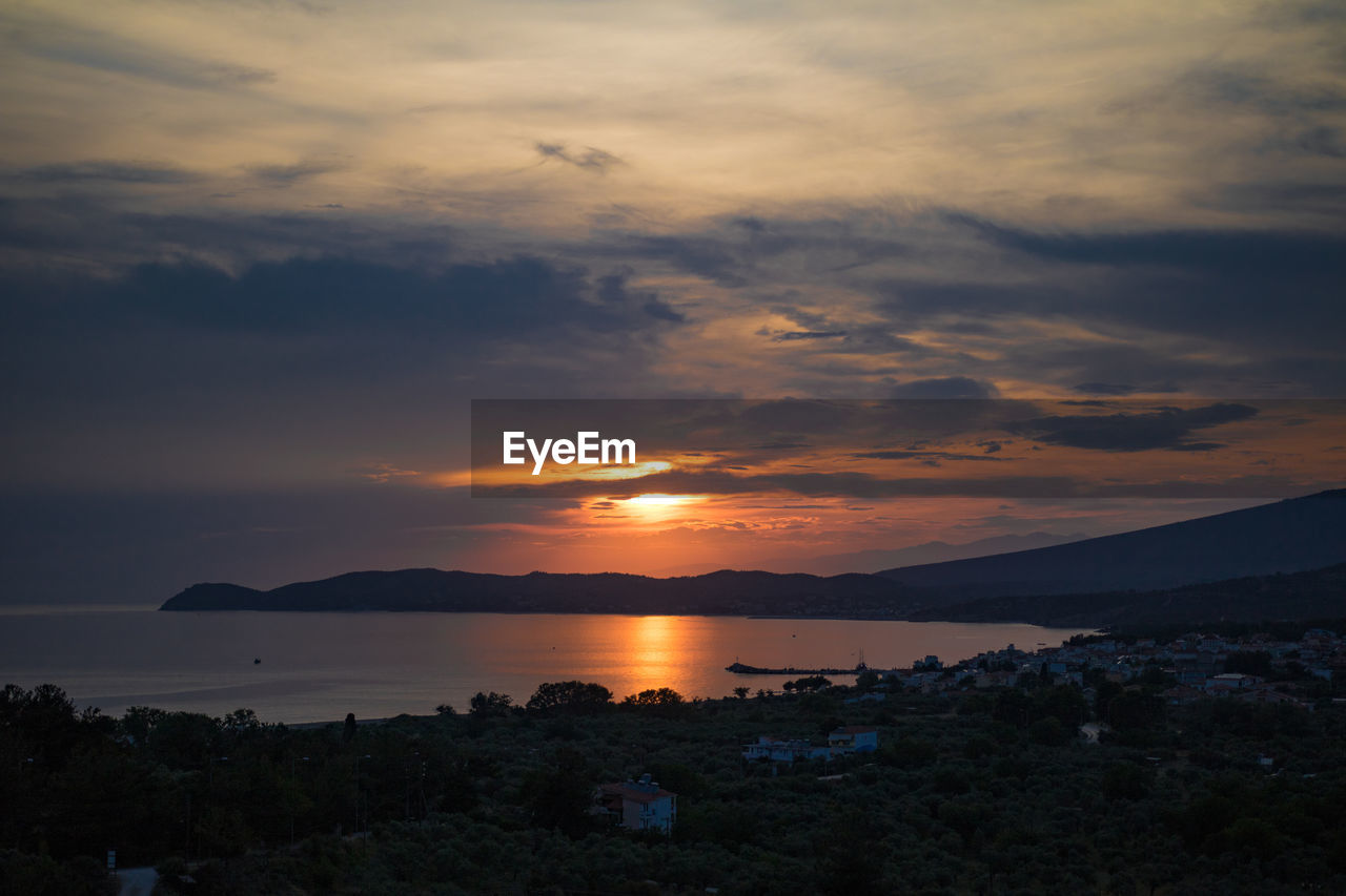 Scenic view of sea against dramatic sky during sunset