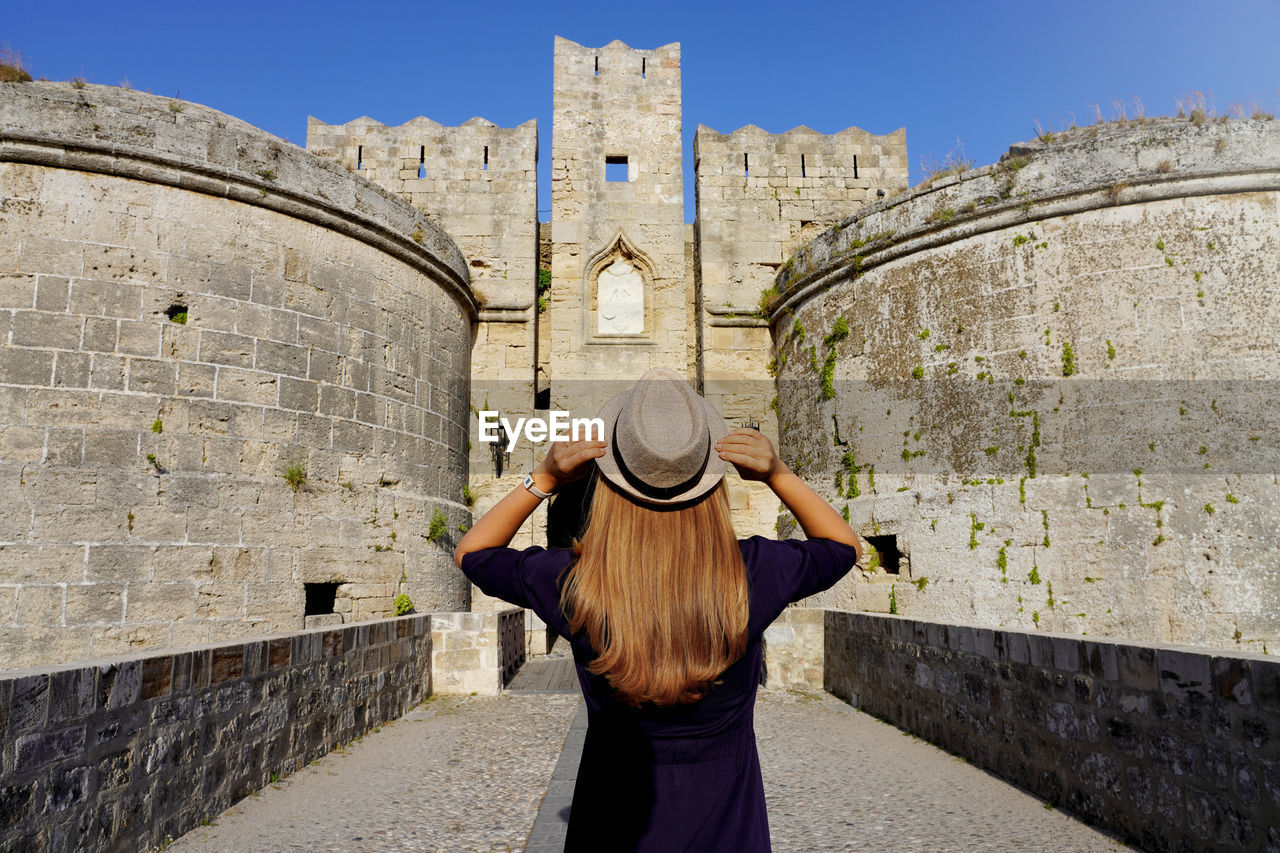 Tourist girl visiting the old fortifications of rhodes city, greece. unesco world heritage site.