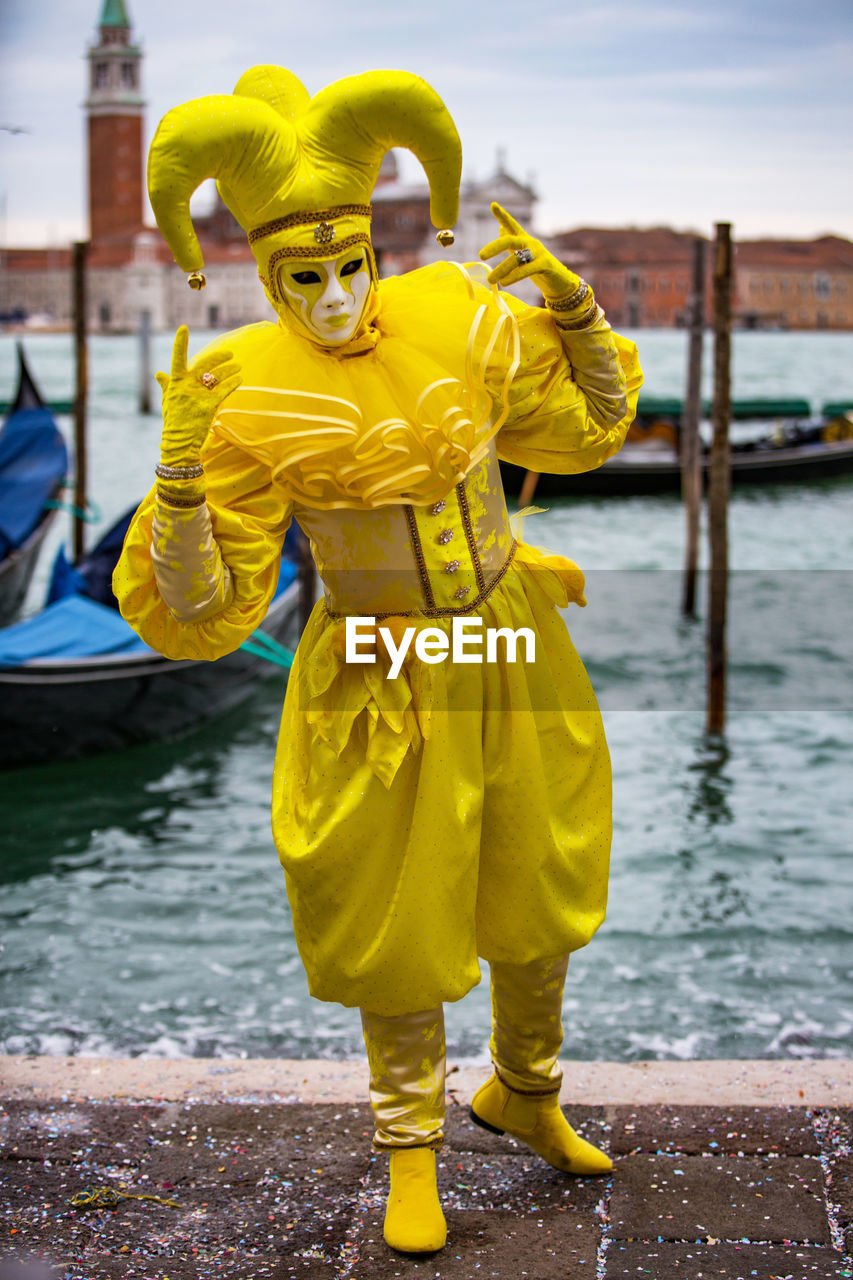 Man wearing venetian mask while standing by sea against sky