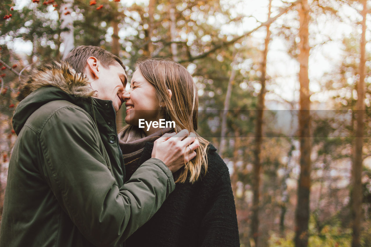 Smiling couple embracing against trees
