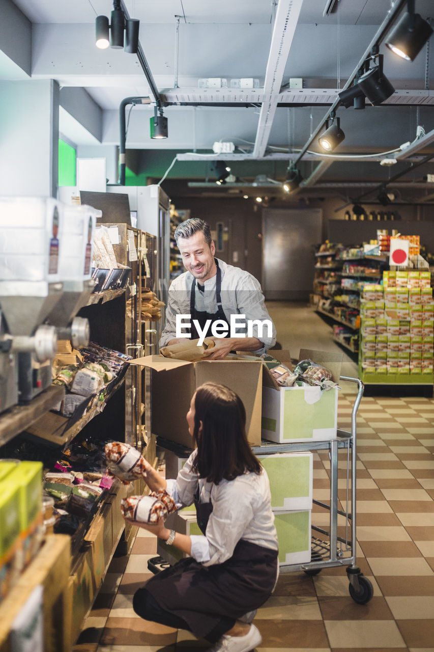 Entrepreneurs arranging packets on shelves in supermarket