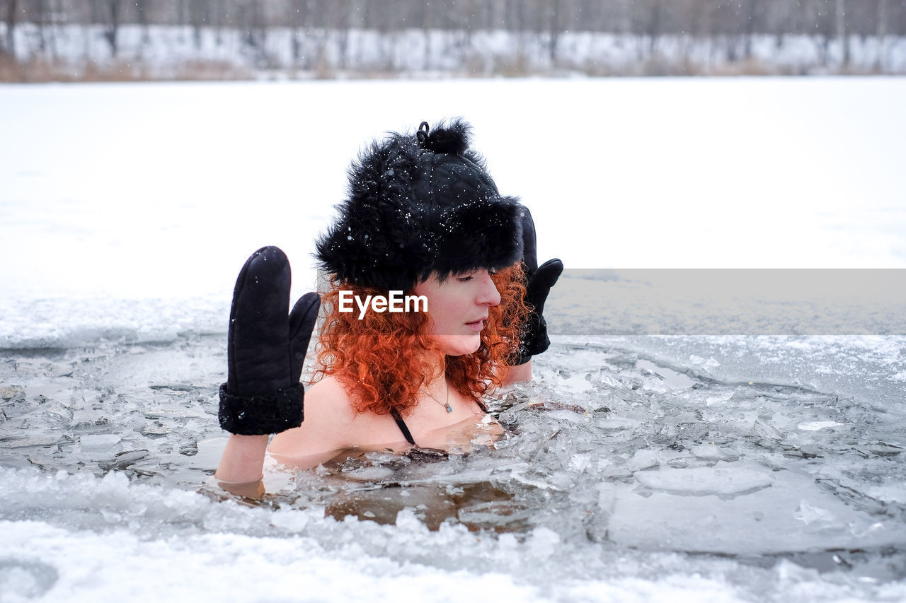 rear view of young woman swimming in snow