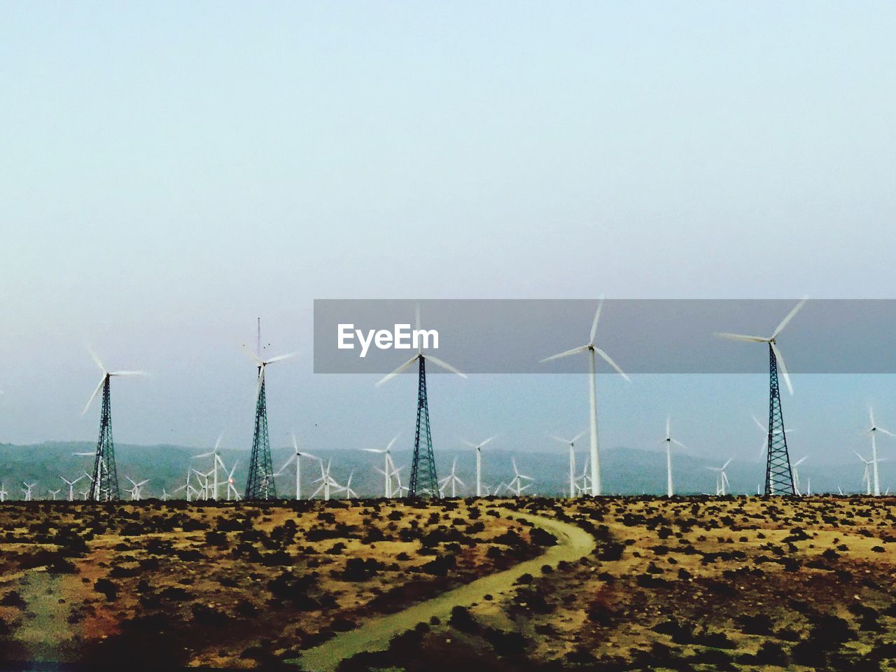 WINDMILLS ON FIELD AGAINST SKY