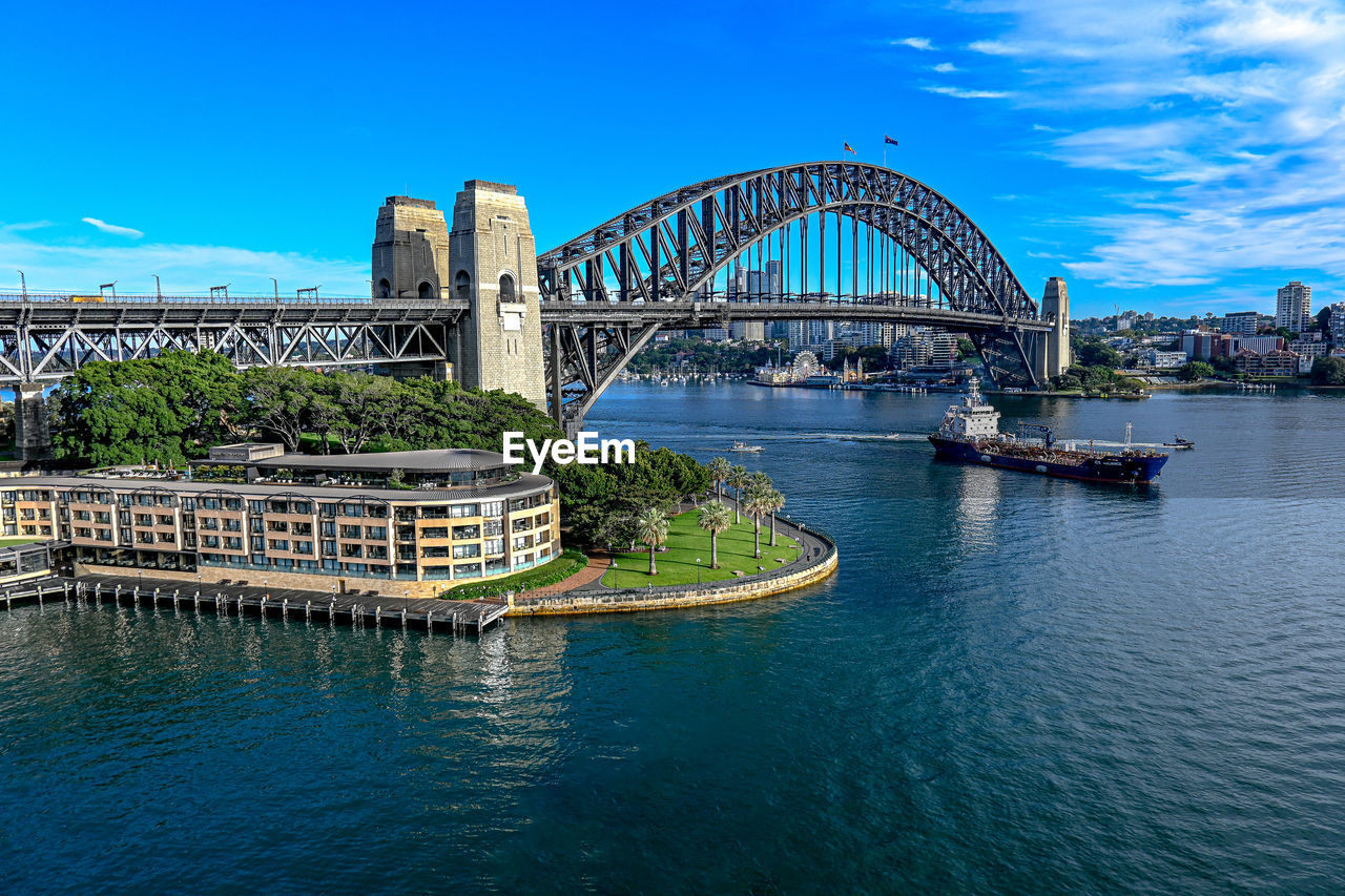 architecture, built structure, water, travel destinations, city, landmark, bridge, travel, building exterior, transportation, sky, nature, tourism, sea, blue, harbor, vacation, building, cityscape, landscape, arts culture and entertainment, arch bridge, nautical vessel, outdoors, no people, urban skyline, waterfront, skyscraper, trip, office building exterior, mode of transportation