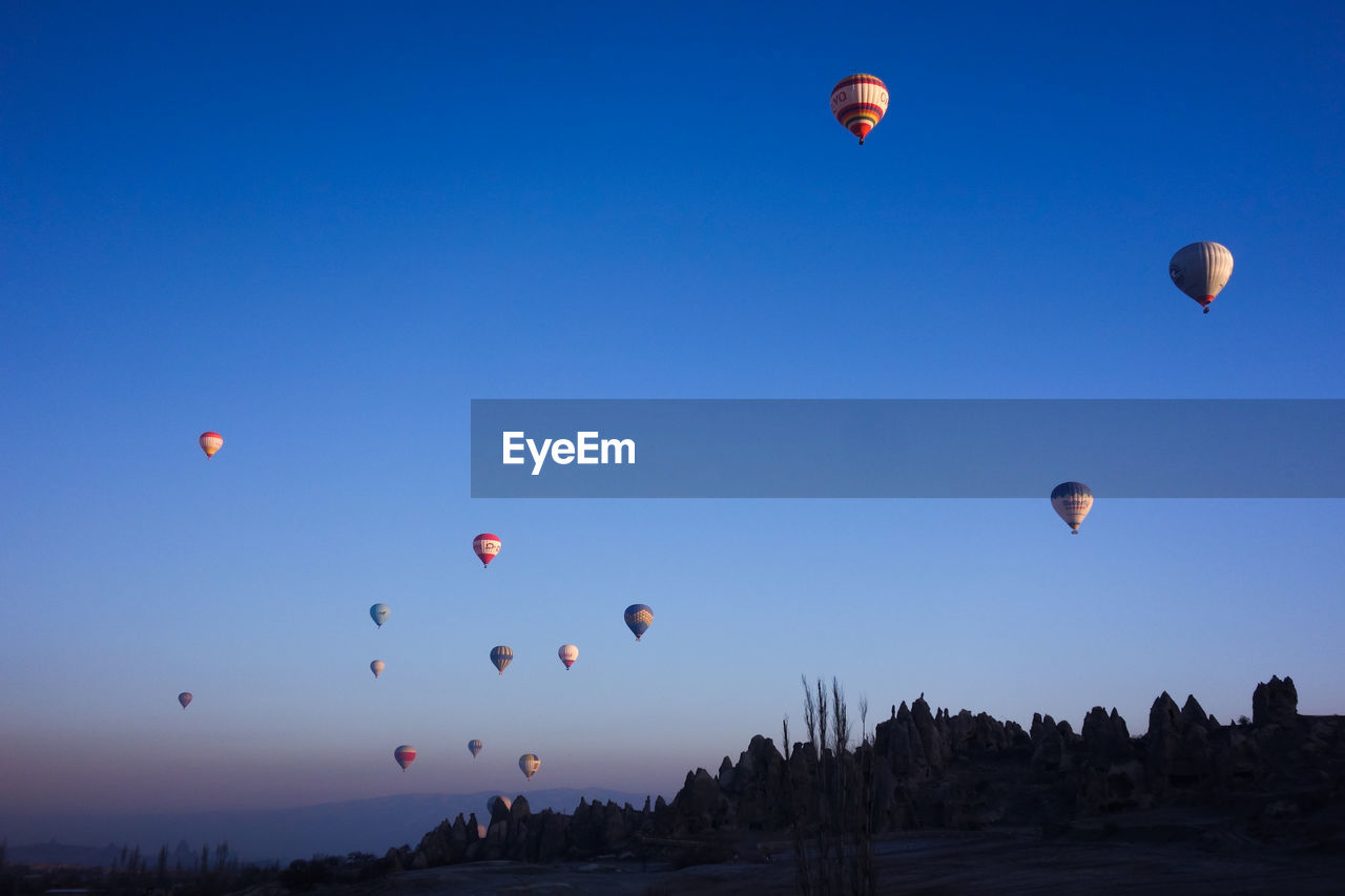 Low angle view of hot air balloon flying against clear blue sky during sunset