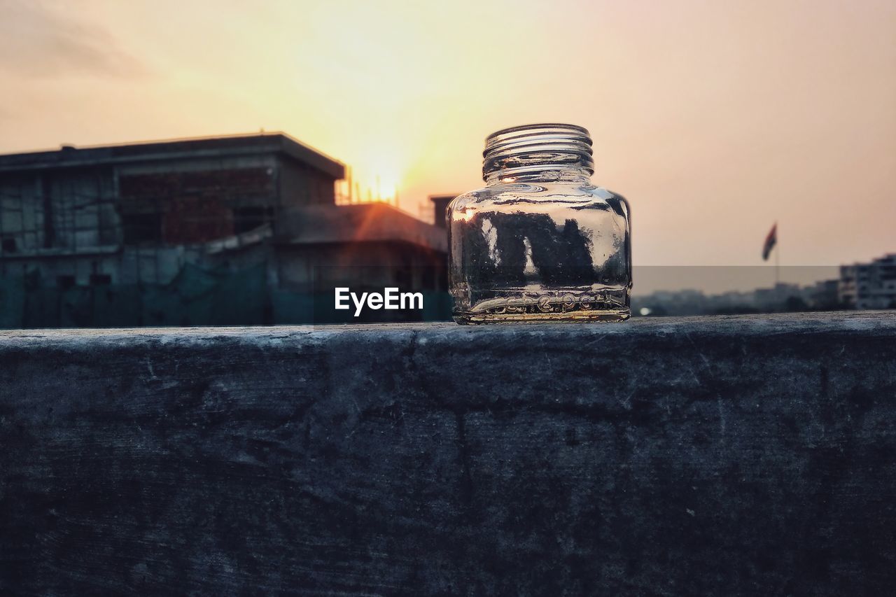 Close-up of old building against sky during sunset with a glass bottle