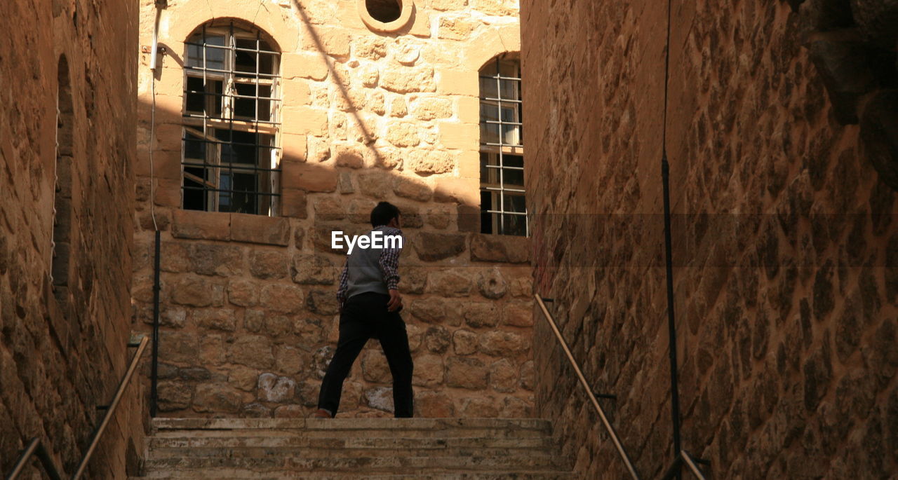 Low angle view of man walking by residential building in town