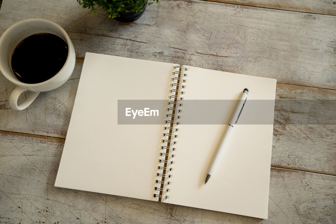 HIGH ANGLE VIEW OF COFFEE CUP ON BOOK