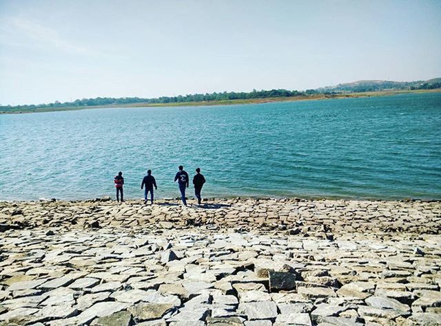 PEOPLE STANDING ON ROCKS AT SHORE