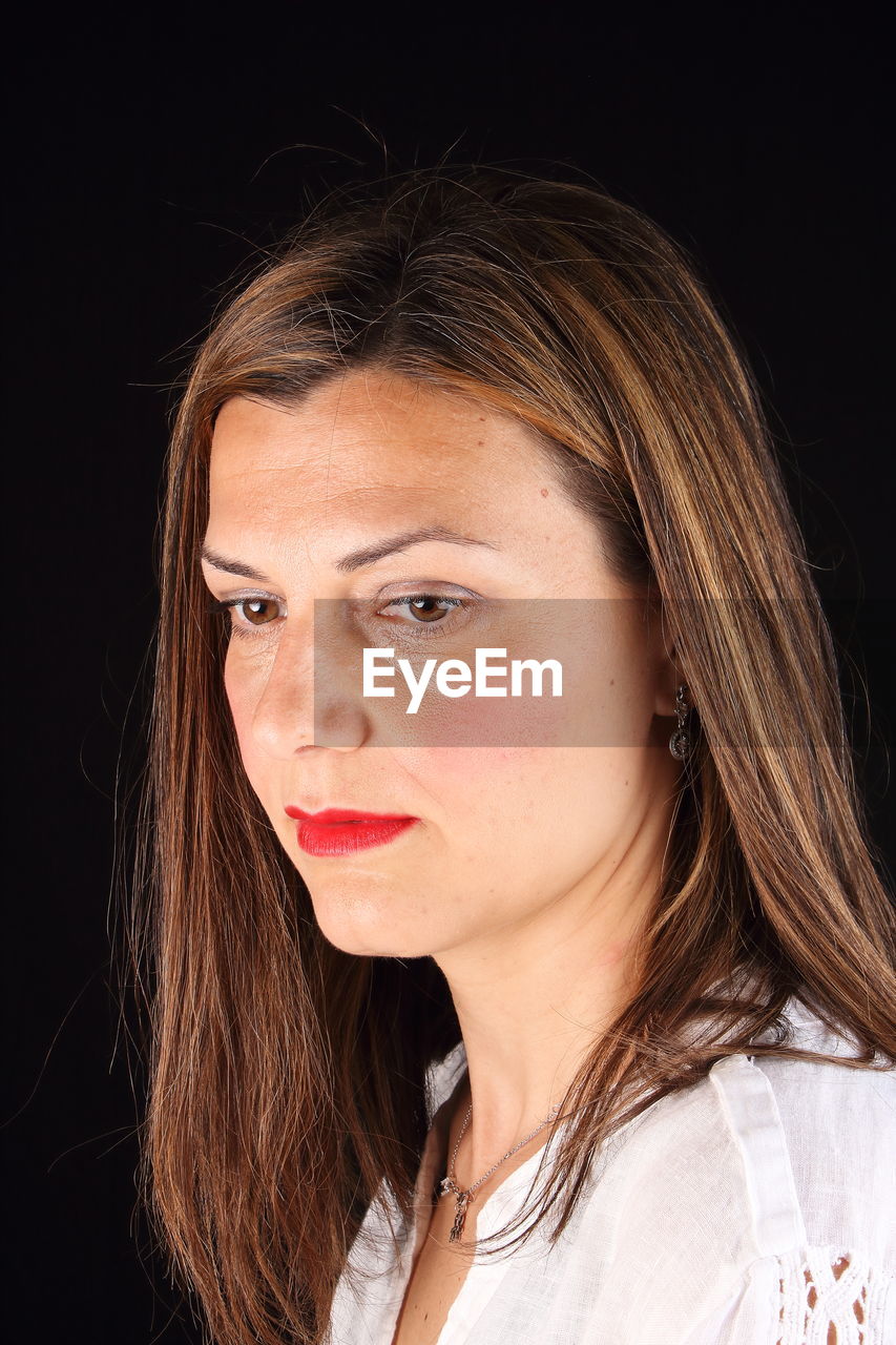 CLOSE-UP OF WOMAN AGAINST BLACK BACKGROUND