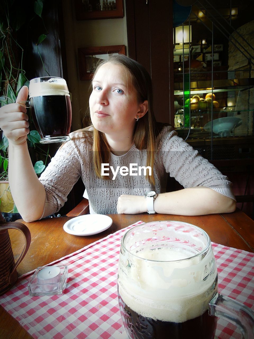 Portrait of young woman holding beer glass in restaurant