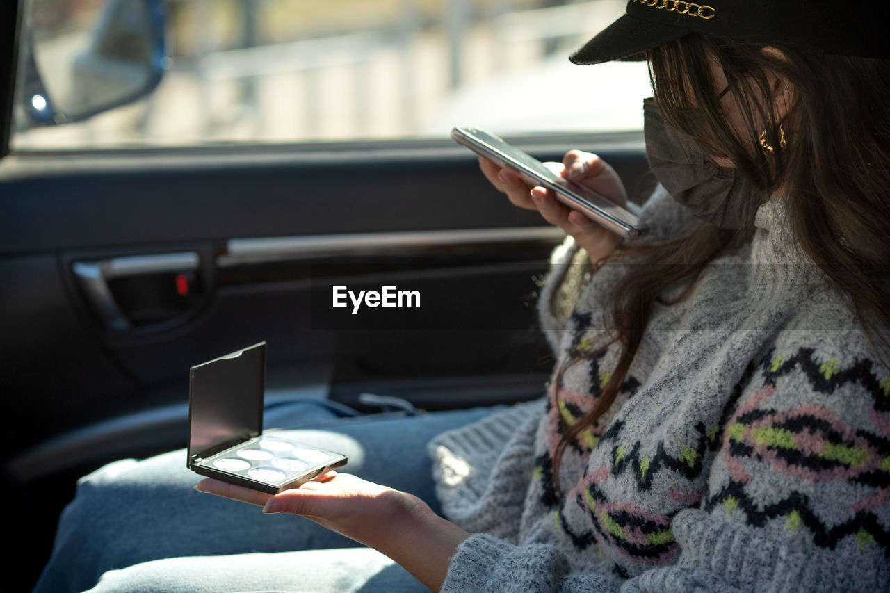 The girl bought a new palette with eye shadows sitting in the car looking at the eyeshadows 