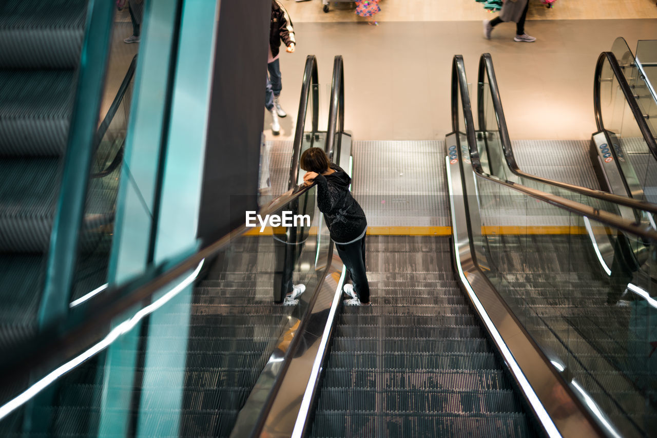 High angle view of boy standing on escalator