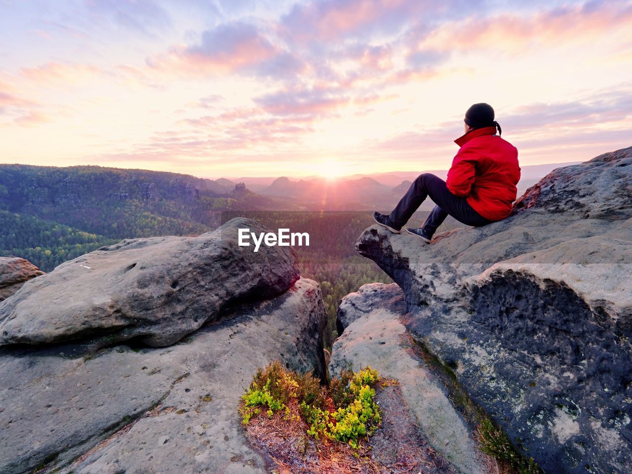 Hiker man take a rest on mountain peak. man lay on summit, bellow autumn valley. 