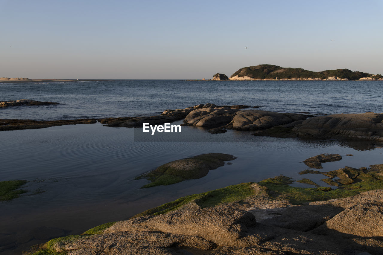 water, sea, sky, land, body of water, rock, shore, beach, ocean, coast, nature, scenics - nature, beauty in nature, horizon, environment, landscape, travel destinations, clear sky, coastline, travel, terrain, wave, tranquility, cliff, no people, sunset, cove, bay, horizon over water, seascape, outdoors, tourism, tranquil scene, architecture, trip, holiday, vacation, blue, reflection, animal wildlife, dusk, idyllic, non-urban scene, sunny, motion, bay of water