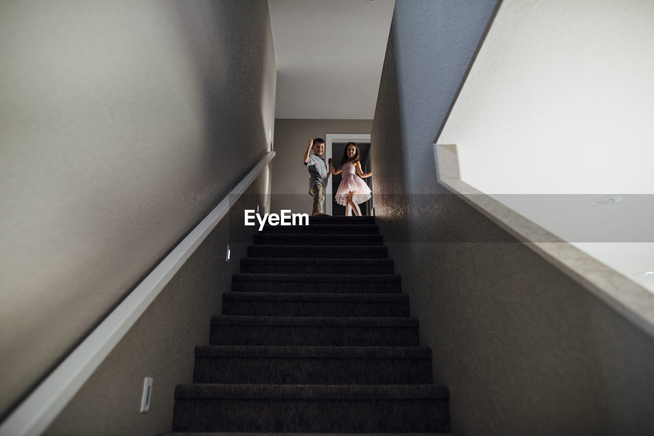 Low angle view of siblings standing on steps at home