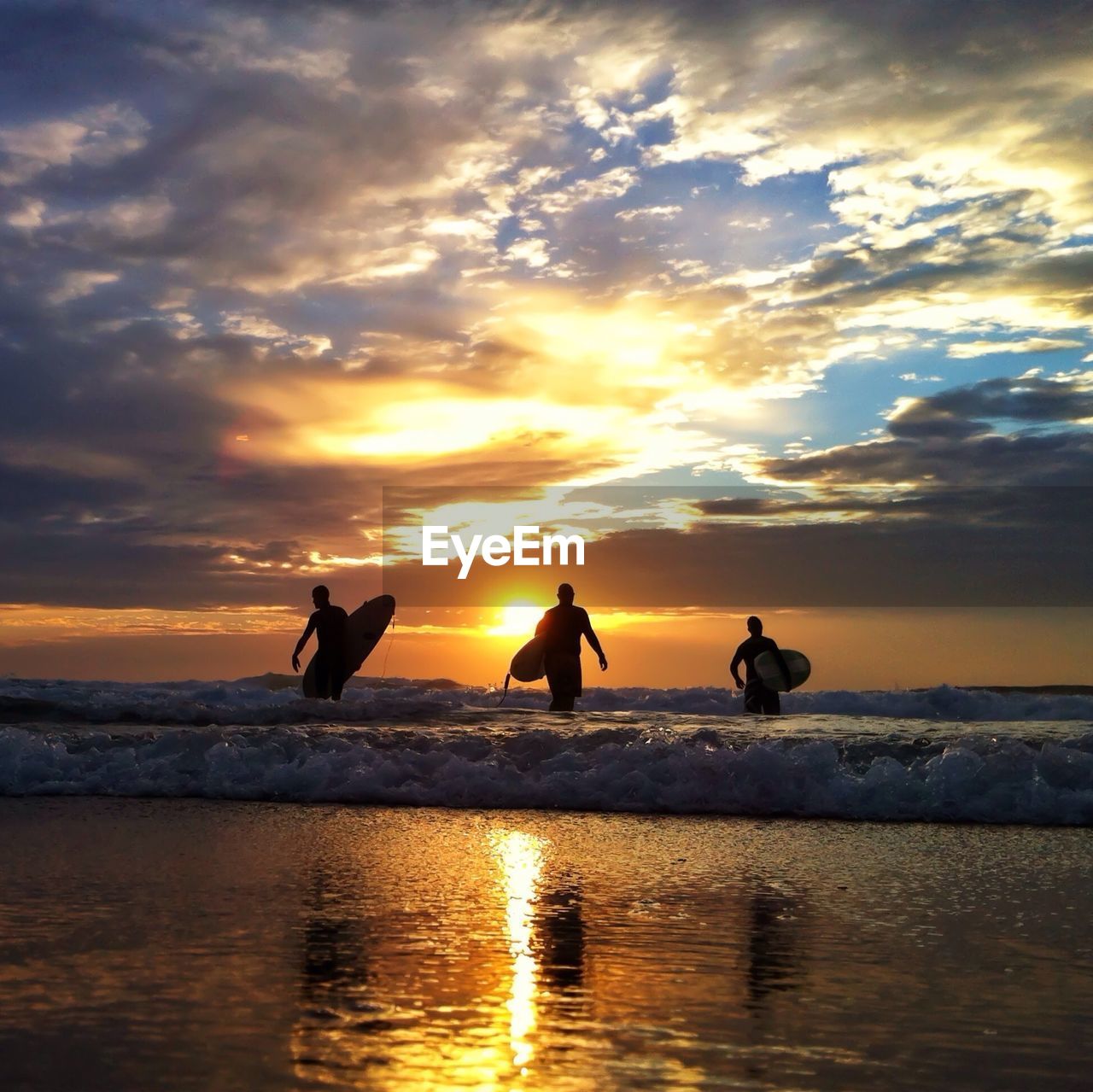 Silhouette of surfboarders walking on beach