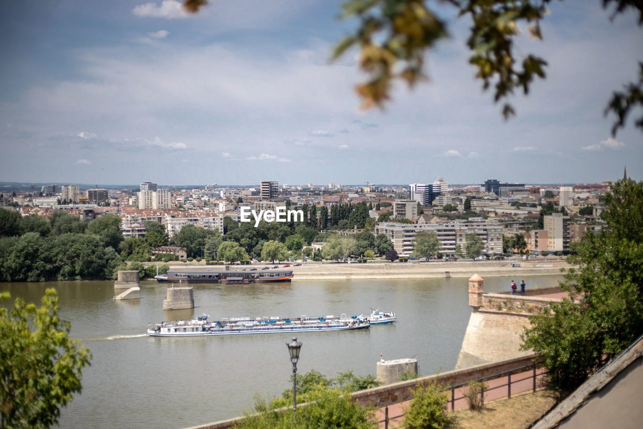 High angle view of town buildings by river against sky