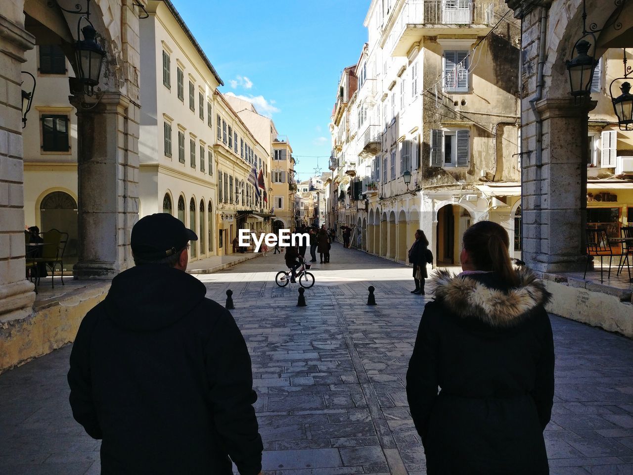 Rear view of people walking on street amidst old buildings in city