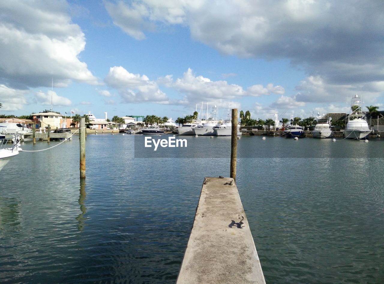 Scenic view of harbor against cloudy sky