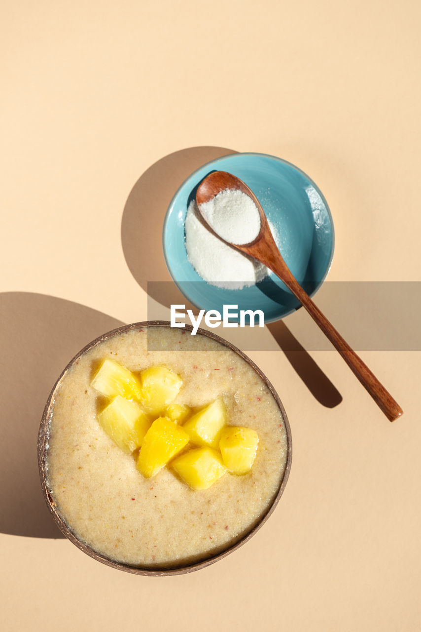 Collagen powder and smoothie from banana, pineapple and gluten free oats in the coconut shell bowl,