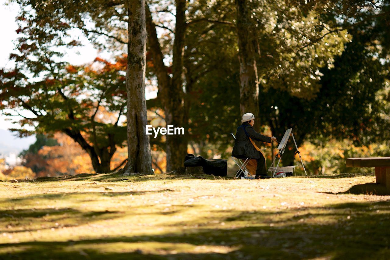 SIDE VIEW OF MAN SITTING ON PARK