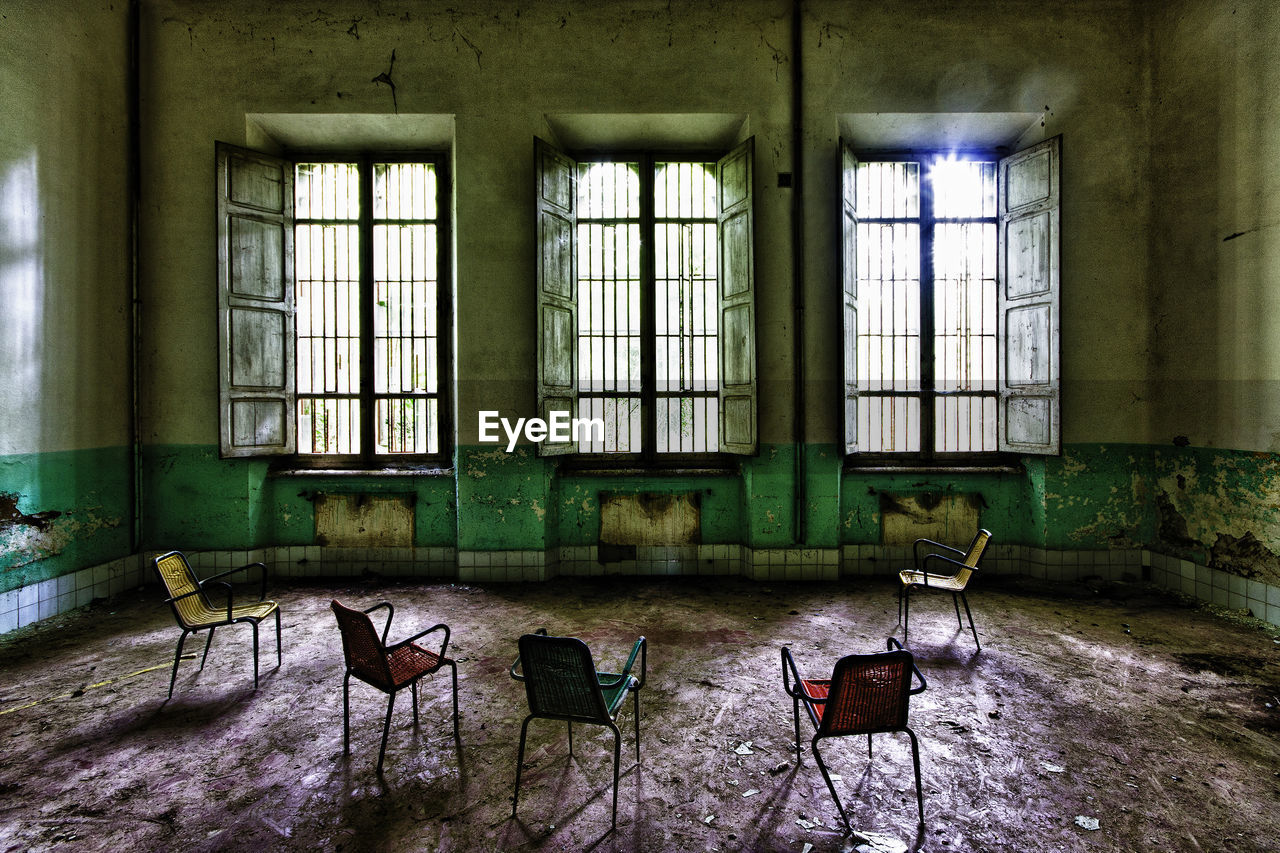 EMPTY CHAIRS AND TABLES IN ABANDONED BUILDING