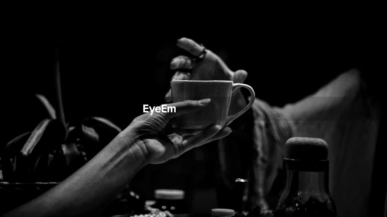 Close-up of hand holding coffee cup in darkroom