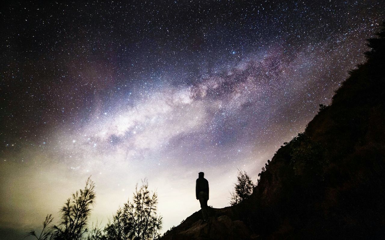 Silhouette man on mountain against star field