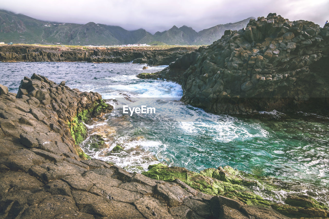 Scenic view of rocks in sea against sky