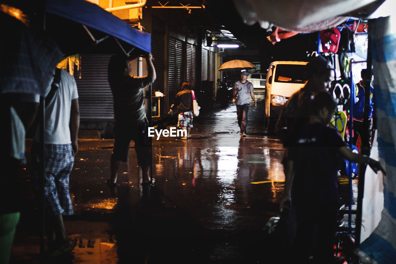 People on market street during monsoon at night