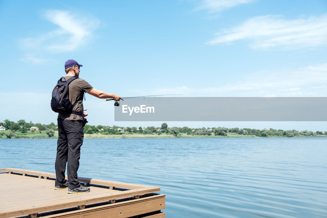 Fisherman with spinning rod on the lake. fisherman with spinning in his hands catching fish at sun