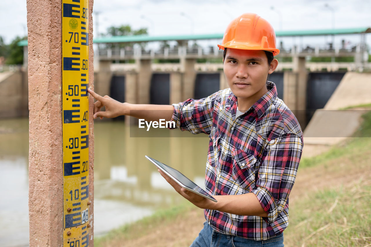 portrait of young man standing in factory