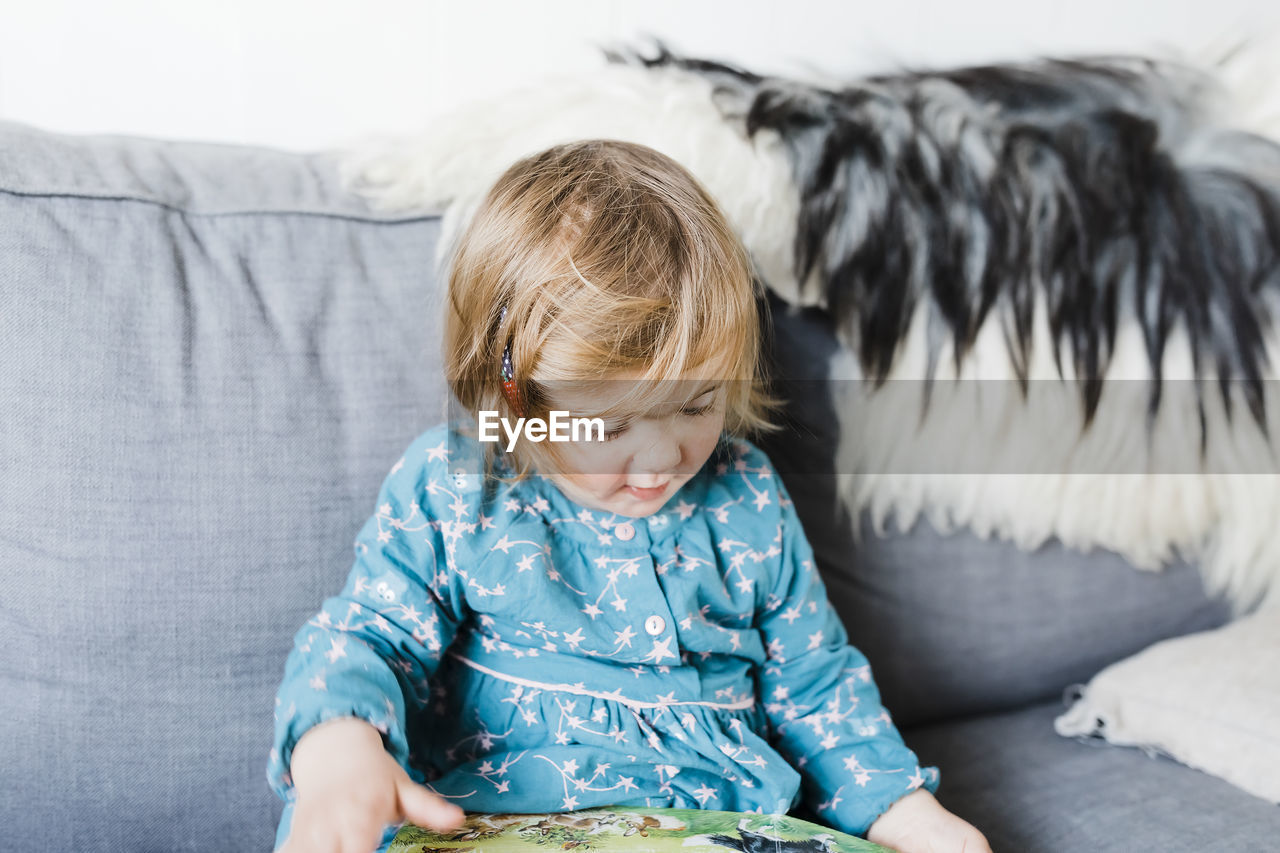 Cute girl sitting on sofa at home