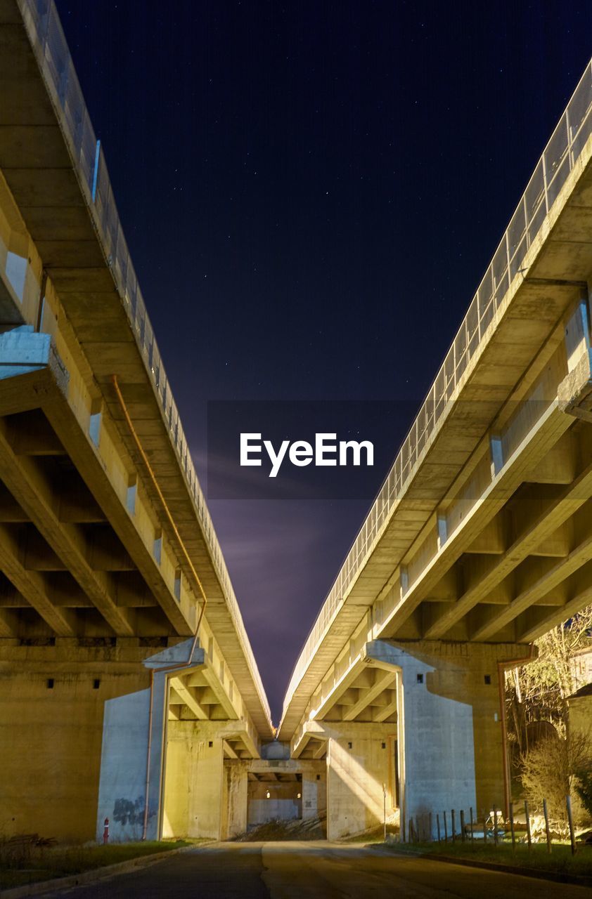 Low angle view of illuminated highway against night sky