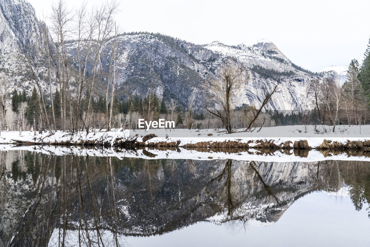 Scenic view of lake by snow covered field against mountain