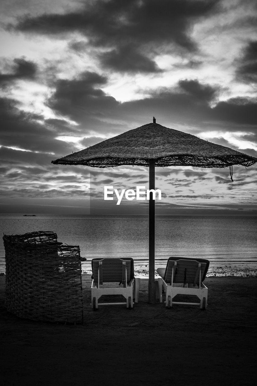 LOUNGE CHAIRS ON BEACH AGAINST SKY