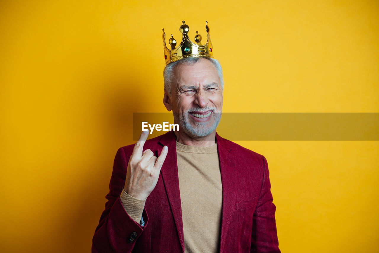 Portrait of smiling man gesturing against yellow background