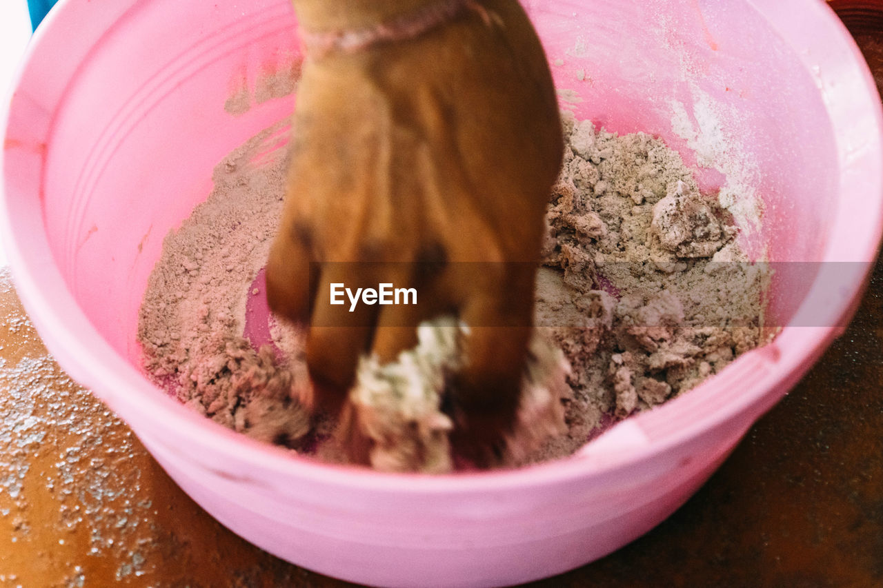 Cropped image of hand making herbal medicine in pink bucket