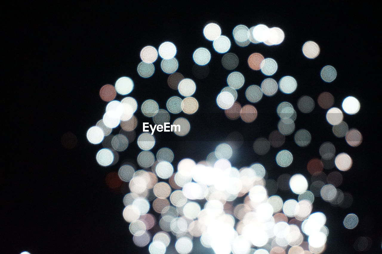 DEFOCUSED IMAGE OF ILLUMINATED LIGHTS AGAINST SKY