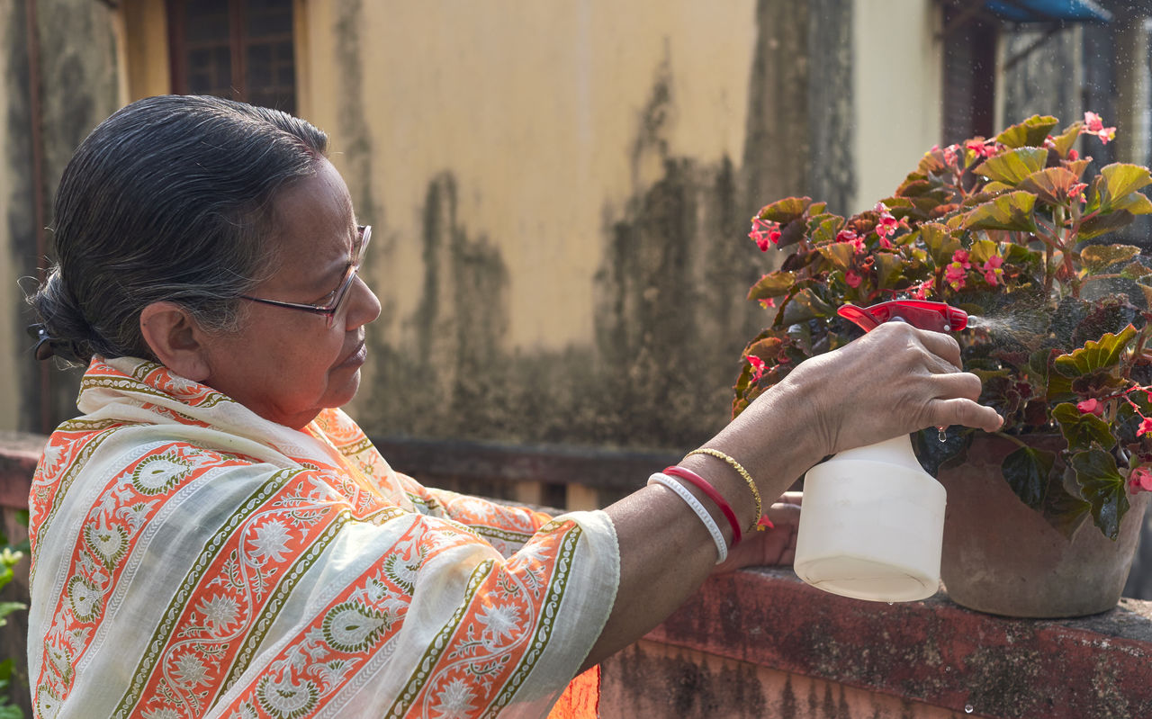 adult, one person, flower, women, flowering plant, nature, architecture, plant, person, lifestyles, temple, female, holding, spring, outdoors, building exterior, clothing, building, tradition, senior adult, floristry, beauty in nature, celebration, built structure, flower arrangement, mature adult, business finance and industry, portrait, day, traditional clothing