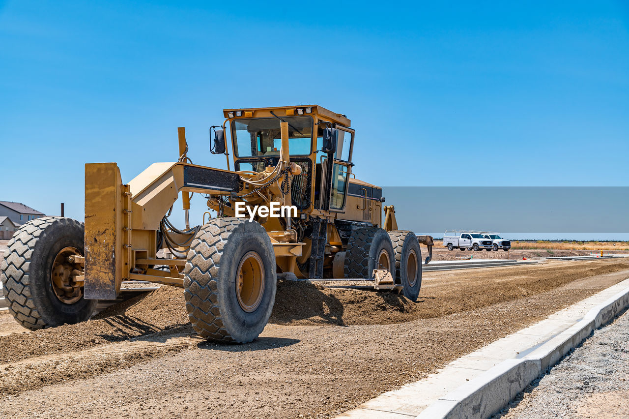 Yellow excavator, road repair. close-up. blue sky background.