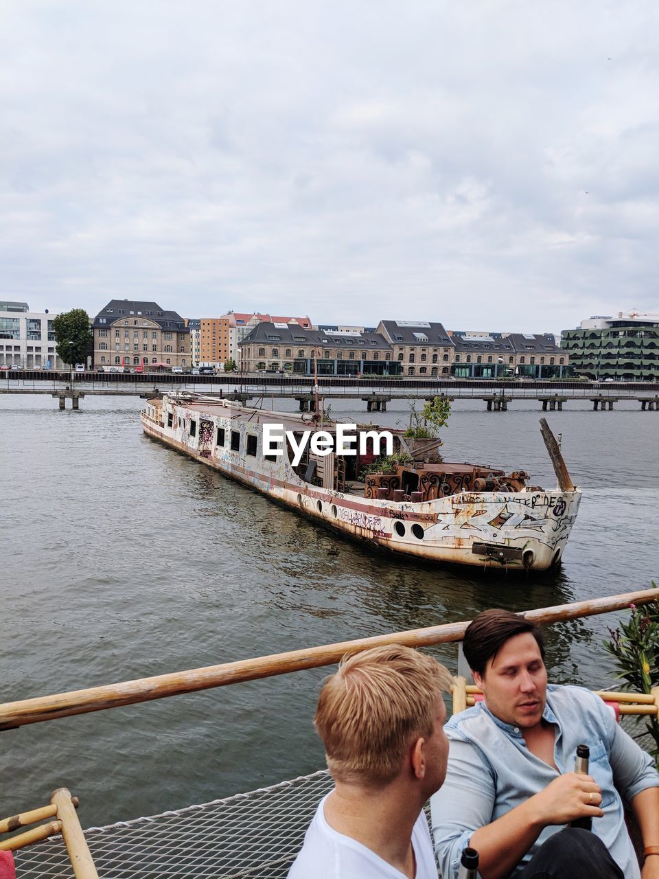 FRIENDS ON BRIDGE OVER RIVER AGAINST SKY IN CITY