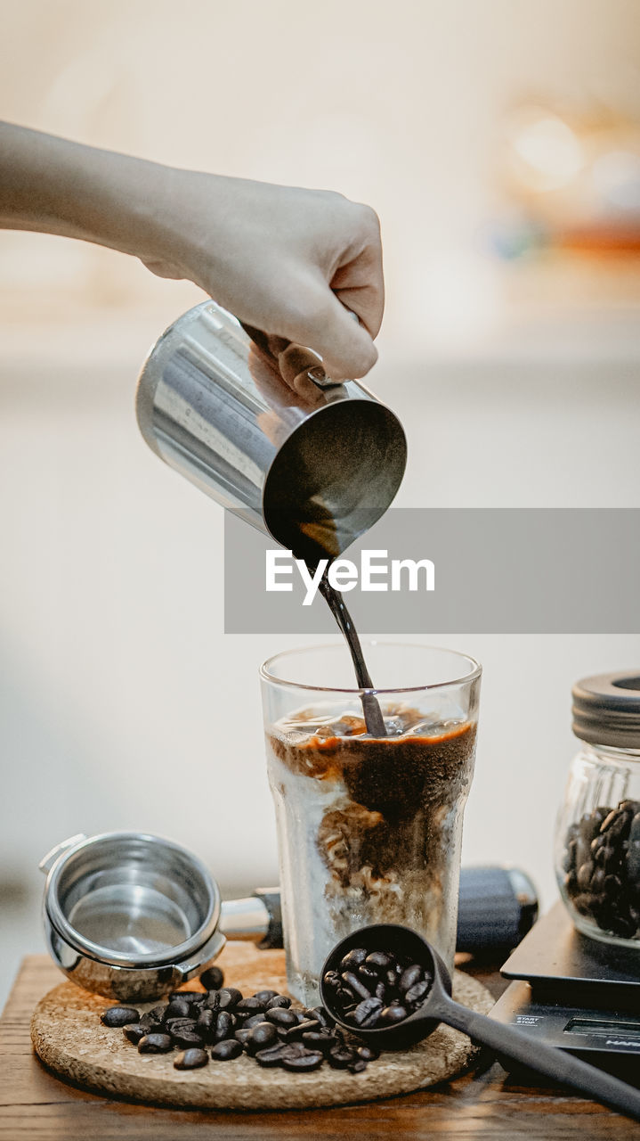 Cropped hand of person pouring coffee on table