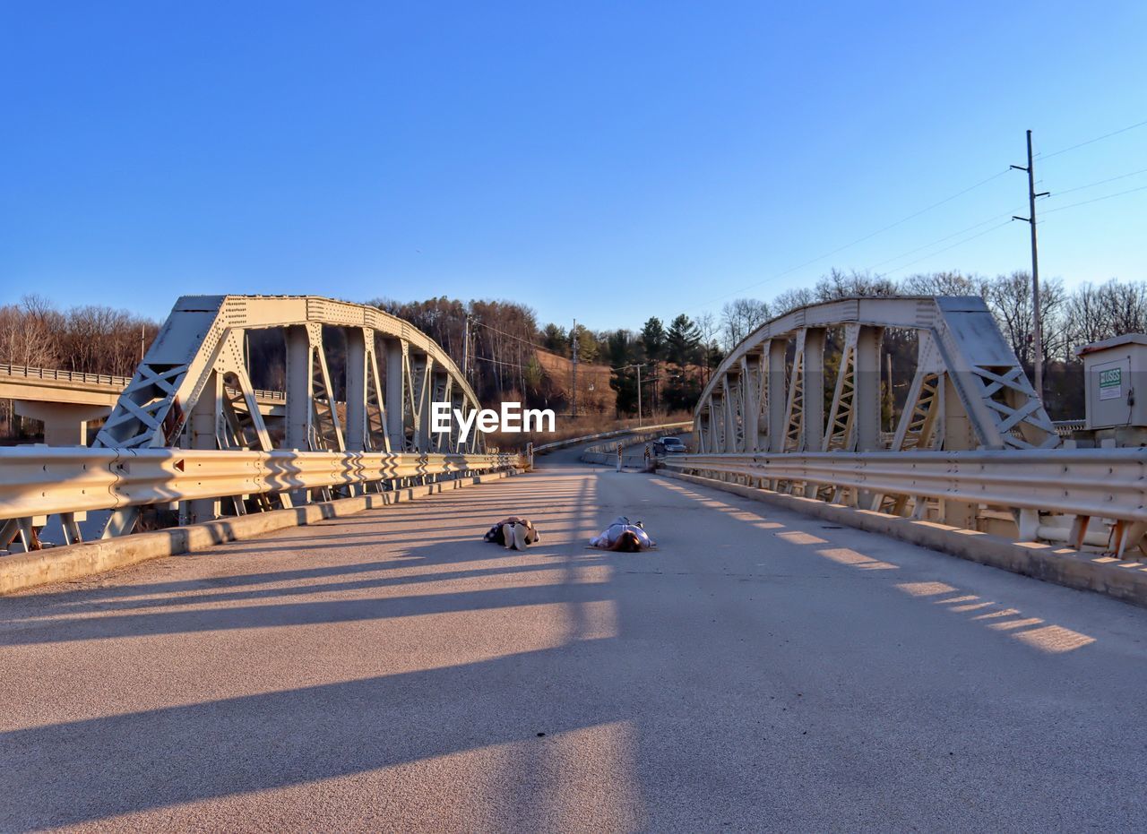 Bridge over road against clear blue sky