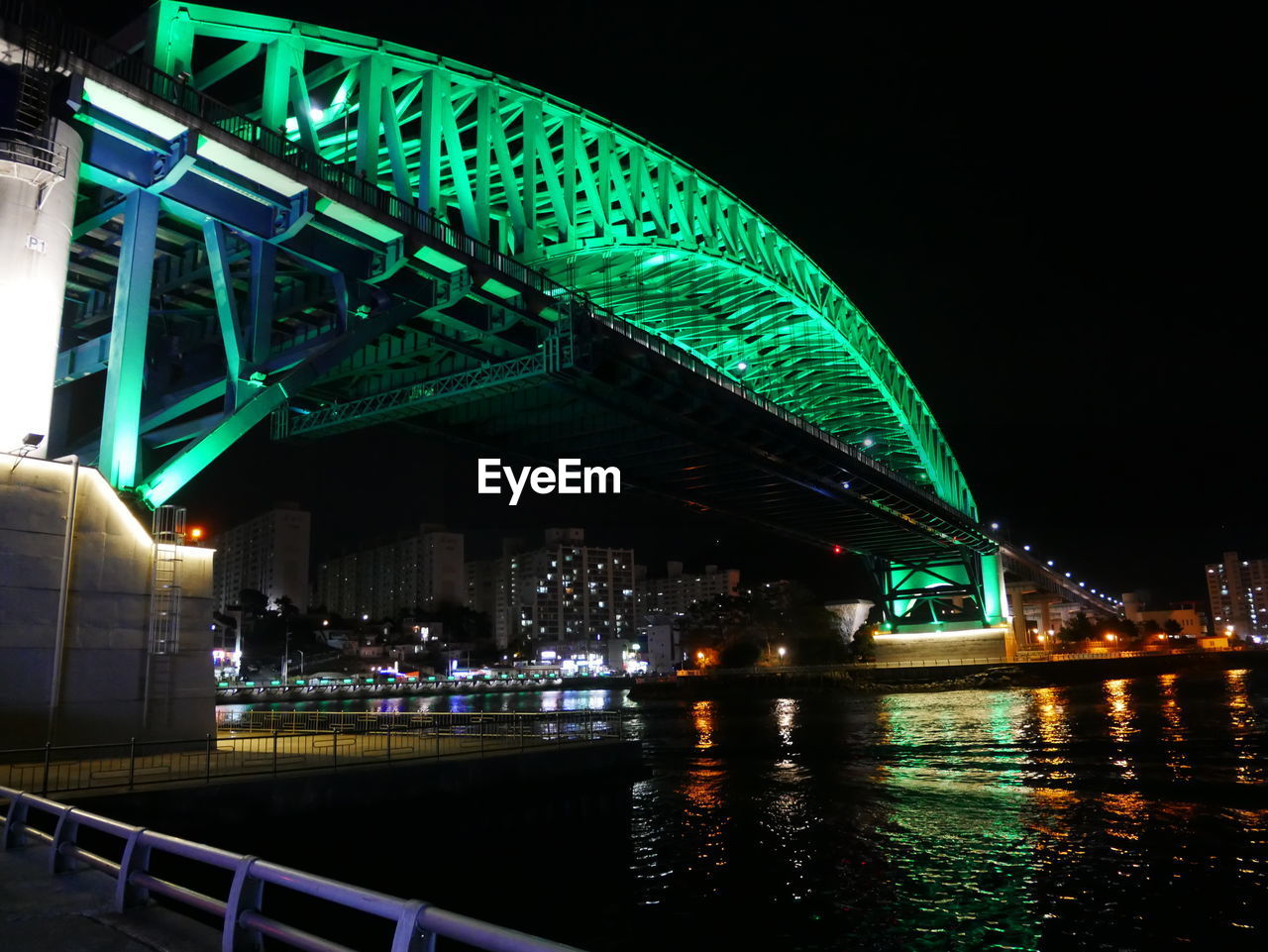 ILLUMINATED BRIDGE OVER RIVER AGAINST SKY