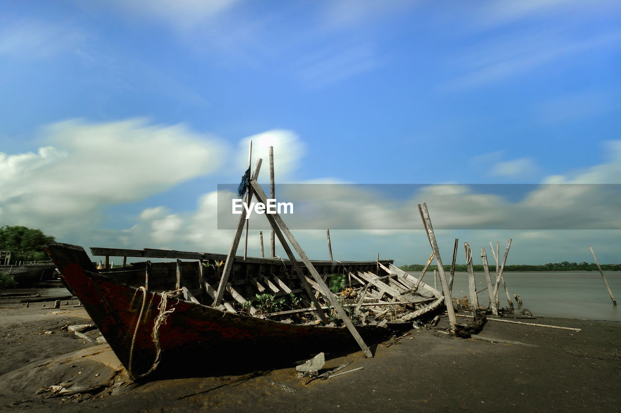 ABANDONED FISHING BOATS ON BEACH AGAINST SKY
