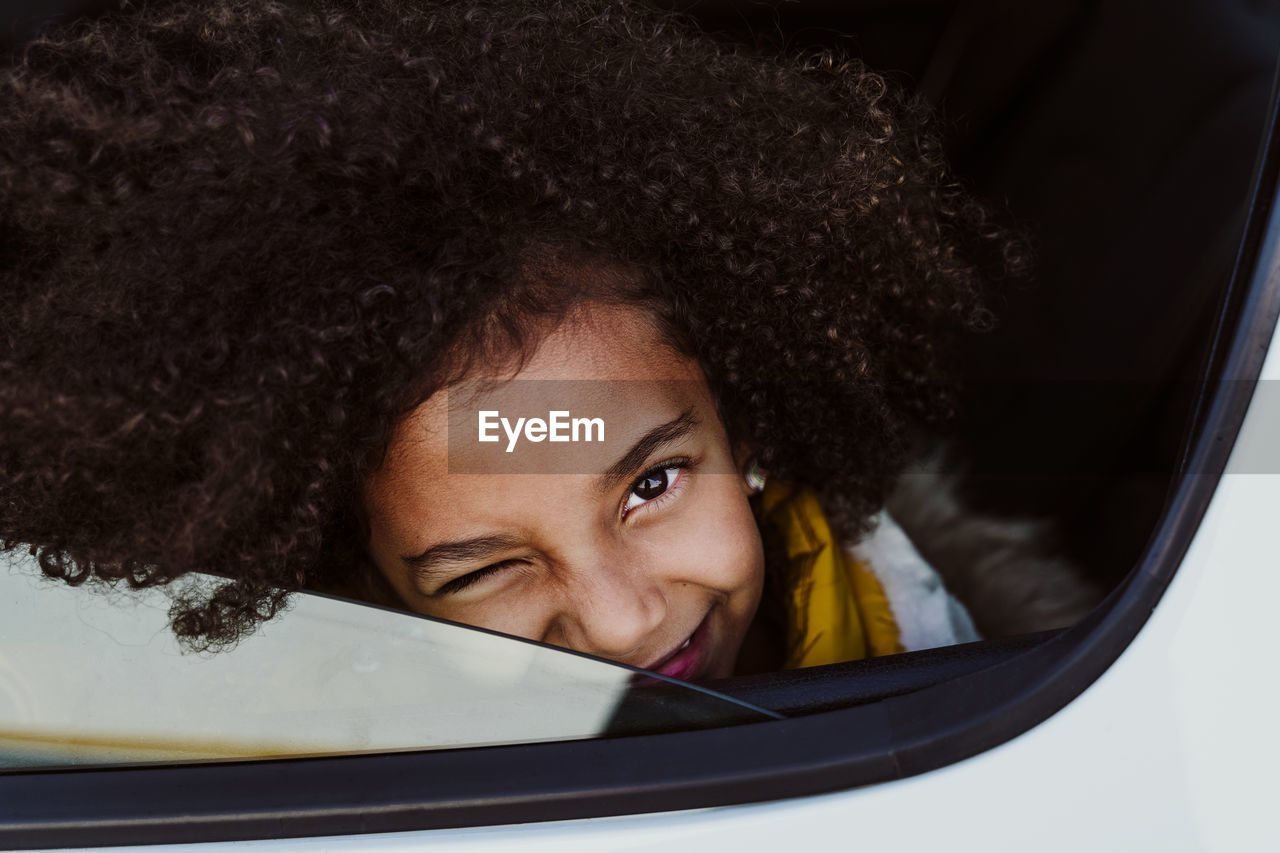 Close-up portrait of girl winking eye in car