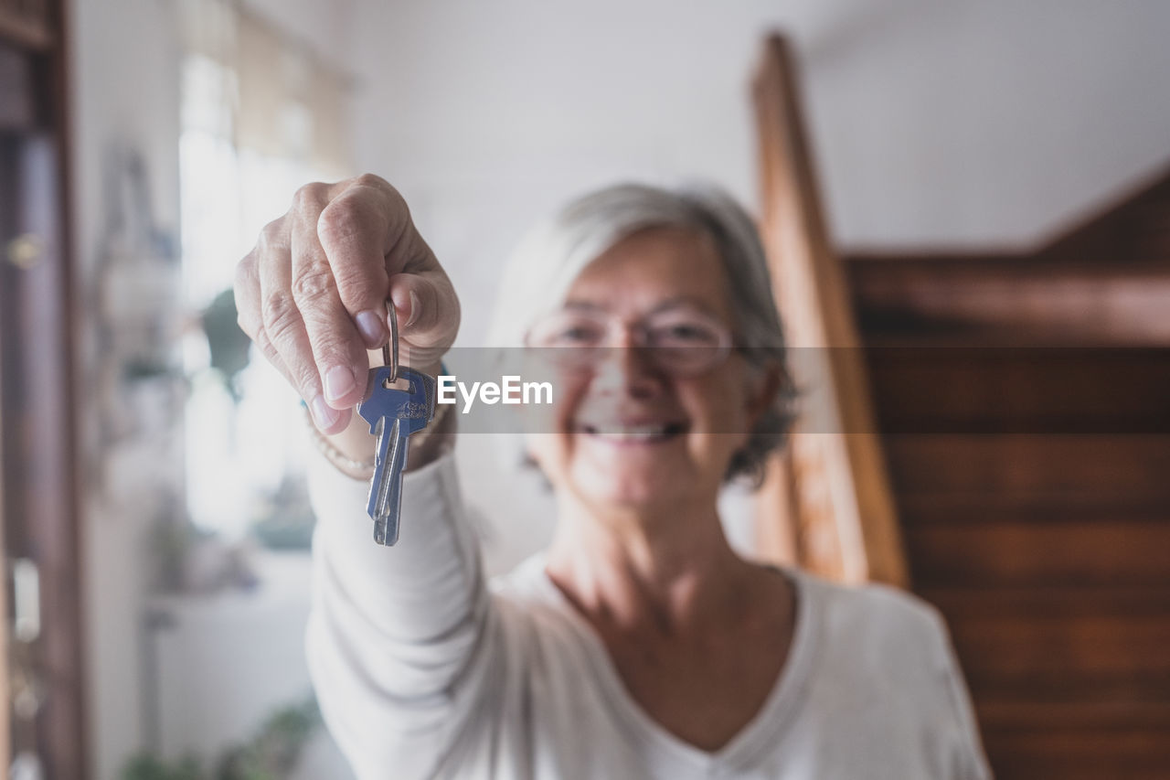 Portrait of senior woman holding key at home